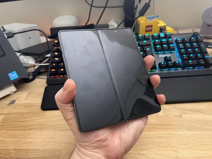 samsung galaxy fold 4 in a hand with the screen off. you can see a slight crease from this angle