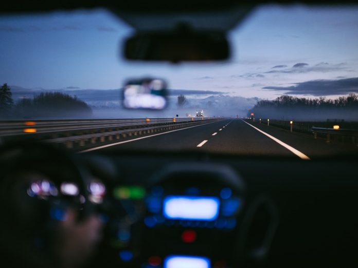 person driving a car at dusk